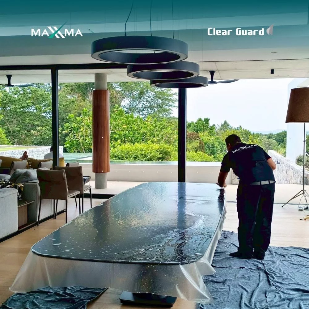 Certified technician installing Clear Guard protective film on a large dining table
