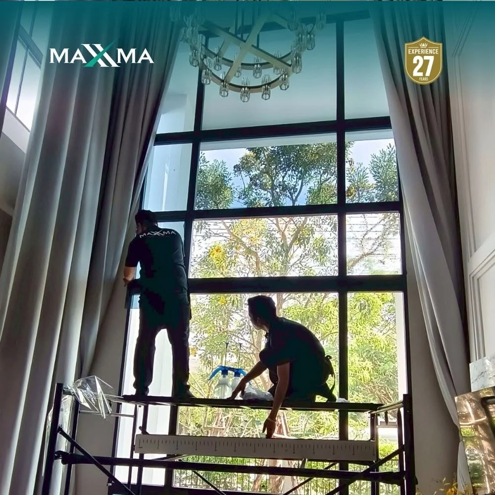 คลิกเพื่อดูภาพขยายเต็มจอ Master technician installing high-durability MAXXMA safety film on large architectural glazing